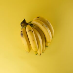 A vibrant bunch of ripe bananas on a matching yellow background, evoking freshness.